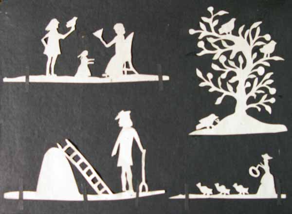 Four White Paper Silhouettes of a Man, a Woman and Young Child, a Tree with Birds, a Man with a Pitch Fork and a Woman with Birds.